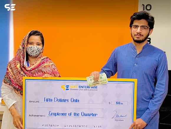 Employee of the Quarter award ceremony at Soft Enterprise with an employee receiving a check and certificate.