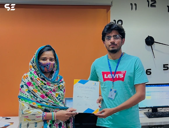 Employee receiving a certificate of recognition from Soft Enterprise at the awards ceremony.