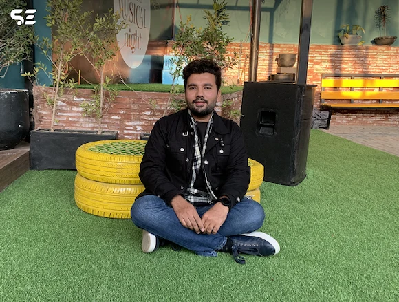 Soft Enterprise team member posing on a yellow chair during the Hi-Tea Gathering event, with a relaxed and casual atmosphere.