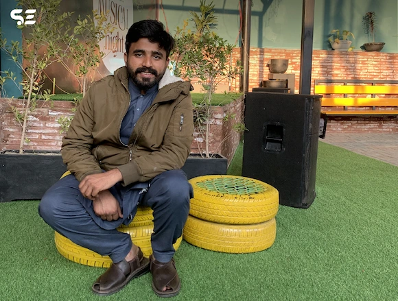 Soft Enterprise team member posing on a yellow chair during the Hi-Tea Gathering event, with a relaxed and casual atmosphere.