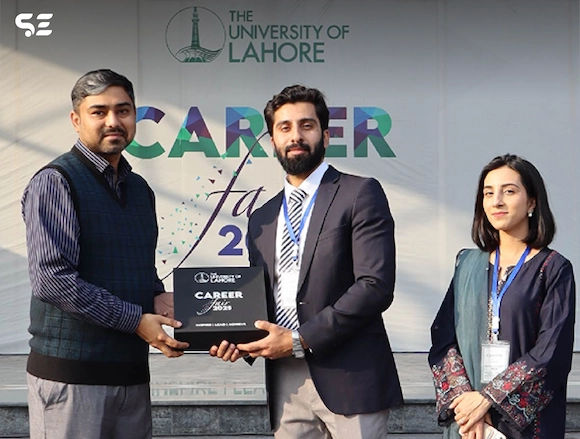 Soft Enterprise CEO receiving an award at the University of Lahore Career Fair 2025, with a banner in the background.