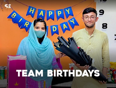 Woman in hijab and colleague celebrating with balloons for team birthdays