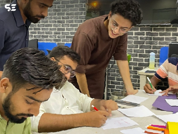 Two male employees working on a craft project at a desk
