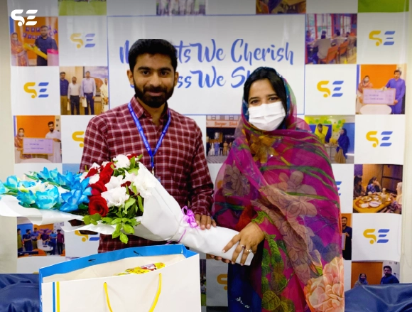Employee presenting flowers to a colleague wearing a face mask