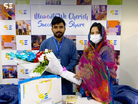 Female employee presenting flowers and a gift to a senior colleague at office event