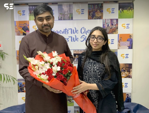 Male and female colleagues posing with a bouquet of flowers