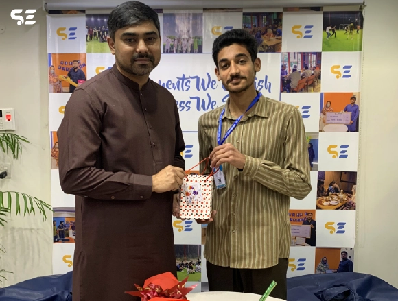 Two employees posing with a framed certificate