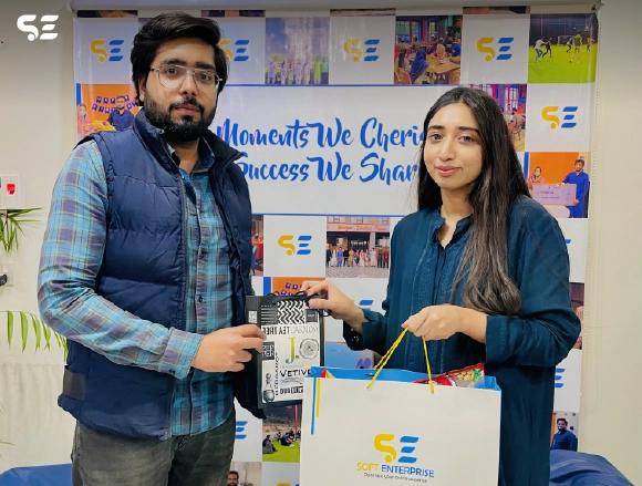Male and female colleagues posing together with a gift bag