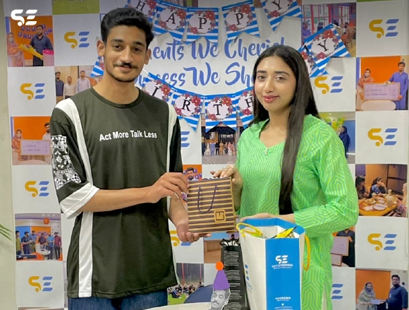 Two employees in green attire smiling together at office event