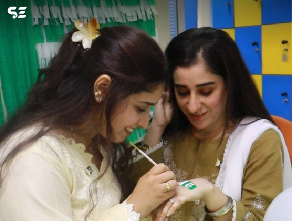 Female colleagues applying green nail polish together
