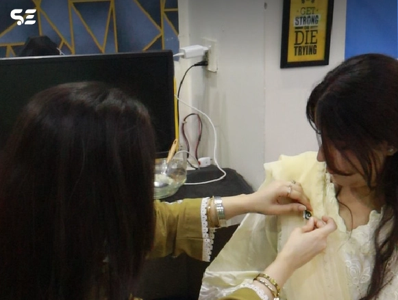 Female employee tying a green ribbon on colleague's wrist