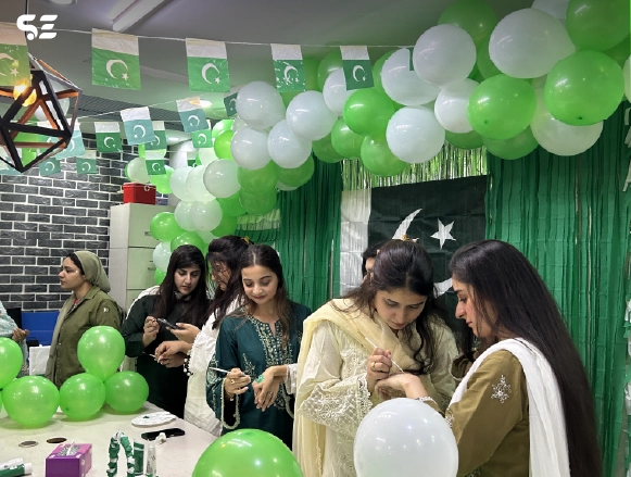 Female colleagues blowing up green and white balloons