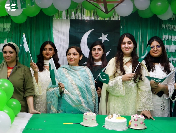 Female colleagues holding sparklers in front of Pakistani flag decor