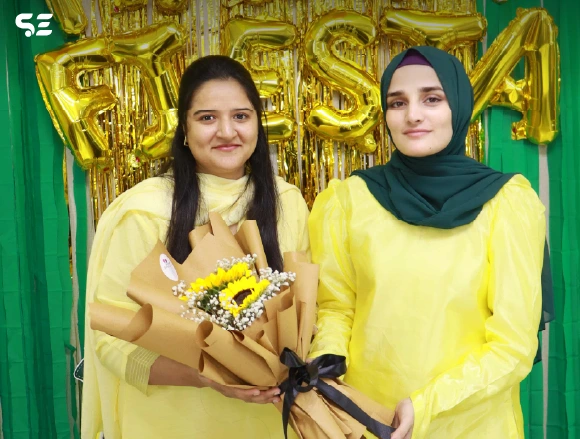 Two female employees posing together holding mango gift baskets