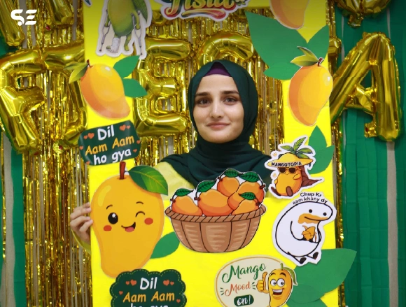 Female employee posing with mango-themed poster and cutouts