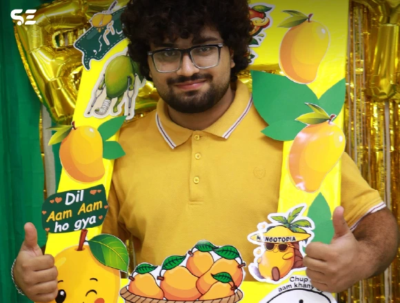 Male employee posing in front of orange and mango-themed wall decor