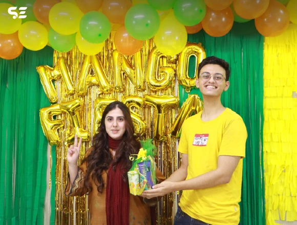 Female and male employee posing together holding mango-themed gifts