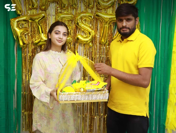 Male and female employee posing with a mango-themed gift basket