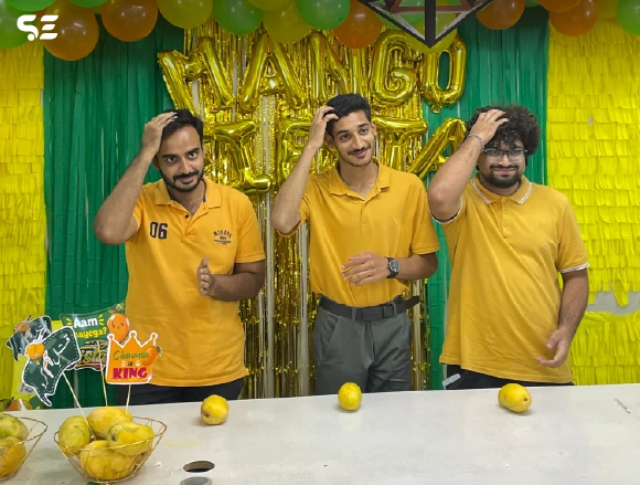Group of male employees posing playfully with mango props