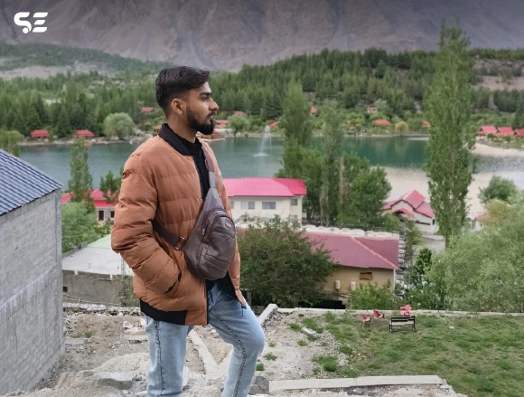 Male employee posing near a lake with mountain scenery