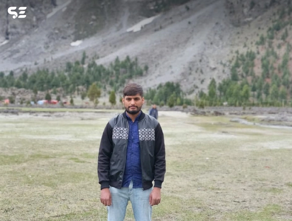 Male employee standing in an open field with mountains in background