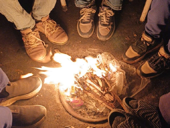 Close-up of shoes near a campfire at night