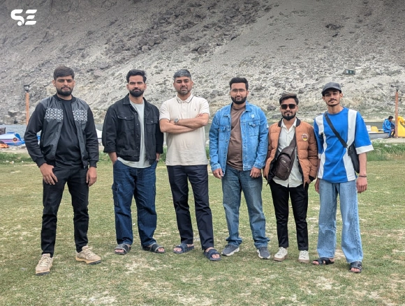 Group of male employees posing outdoors at a rocky campsite