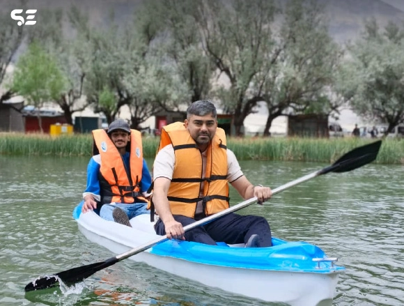 Two men in orange life jackets paddling a kayak together