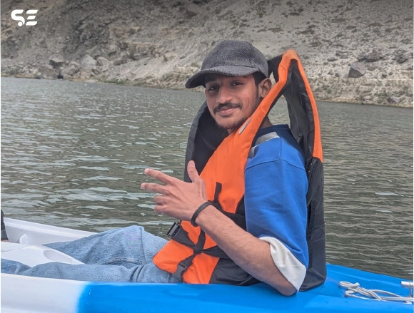 Man wearing an orange life jacket sitting in a rafting boat