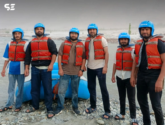 Group of men in orange life jackets posing for a rafting trip