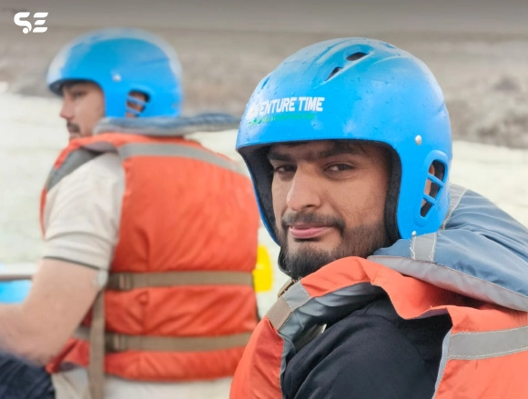 Man in blue helmet and orange life jacket preparing for river rafting