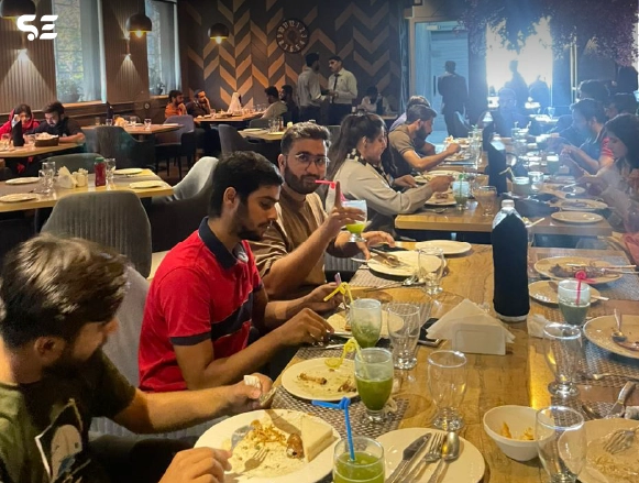 Group of employees eating together at a wooden restaurant table