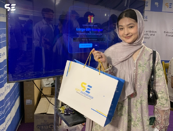 Female employee holding a gift bag at Bidswala event booth